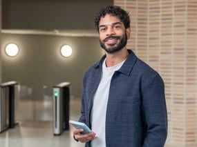 Een persoon met een mobiele teleffon in de hand glimlacht